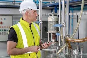 Engineers or factory managers wearing safety helmet inspect the machines in the production line. The inspector opened the machine to test the system to meet the standard. photo