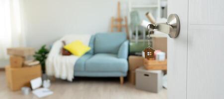 Moving house and relocation. The key was inserted into the door of the new house, inside the room was a cardboard box containing personal belongings and furniture. move in the apartment, banner photo