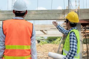 inspector or engineer is inspecting construction and quality assurance new house using a blue print. Engineer or architects or contactor work to build the house before handing over to the homeowner. photo