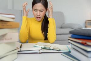 Asian student woman have anxiety because of exams, female prepare for test and learning lessons in the library. stress, despair, haste, misunderstanding reading, discouraged, photo
