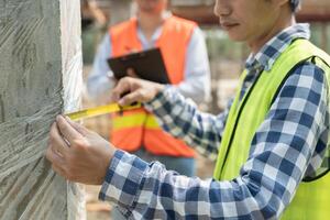 inspector or engineers is inspecting construction and quality assurance check dimension of house by using a tape measurement. Engineers or architects or contactor work to build the house before sell. photo