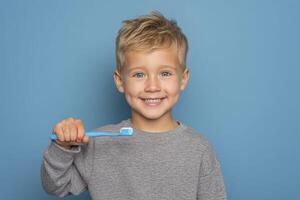 Smiling boy holding a toothbrush on blue background. photo