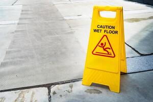 Yellow Caution slippery wet floor sign on the wet ground. Safety Warning in Public Area. Safety Warning Concept. photo