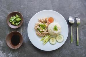 Hainanese chicken rice or nasi hainan or rice steamed with chicken soup served with cucumber slice, broth, and sa photo
