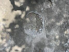 A grey concrete surface with a hole in the middle. The hole is surrounded by gravel and dir photo