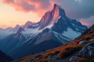 A mountain range with snow capped peaks at sunset photo