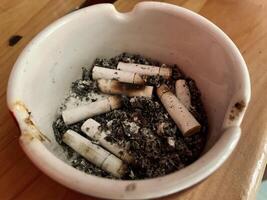Cigarette ashtray full of cigarette ash on the table photo
