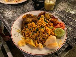 a plate of ifumie noodles on a white plate on a wooden table photo