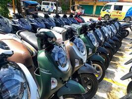 a row of automatic scooters parked in the yard of the Mitra showroom. Indonesia - Sibolga, May 22, 2025 photo