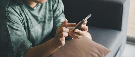 hand of asian woman using smartphone on sofa relaxing and shopping online working from anyware. use of technology. photo