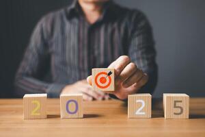 Businessmen hold Target 2025 and wooden cube blocks on the table. start a happy new year 2025. strategy target, goal, plan concept.copy space. photo