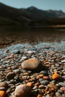 A rock is sitting in the water with a mountain in the background photo