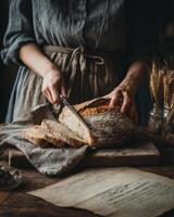 Woman cutting bread on wooden table with book and wheat photo