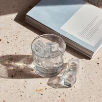 A glass of ice cubes and a book on a table photo