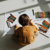 A child drawing on paper with crayons photo