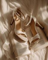 White wedding shoes on a bed with a book photo
