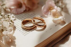 Two wedding rings on an open book with flowers photo