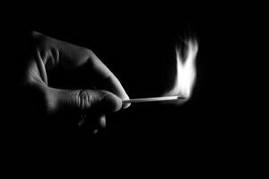 A person holding a matchstick in the dark photo