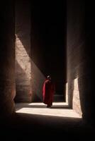A monk walks through a narrow tunnel photo