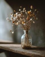 Dried flowers in a glass vase on a wooden table photo