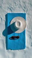 A hat and sunglasses on a blue towel photo