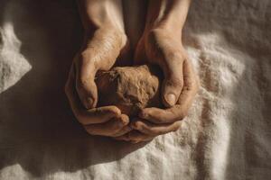 Hands holding a clay ball on a bed photo