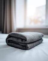 A folded blanket is sitting on a bed photo