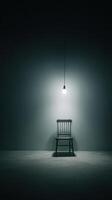 A chair in a dark room with a light bulb photo