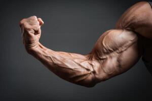 Muscular arm of a bodybuilder on a dark background photo