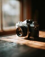 An old camera sitting on a wooden table photo