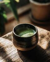 A cup of green tea sits on a wooden table photo