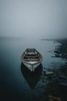 A boat sits on the shore of a foggy lake photo