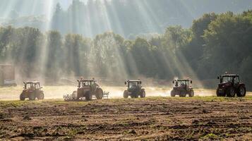 Tractors amid sunrise rays on misty farmland photo