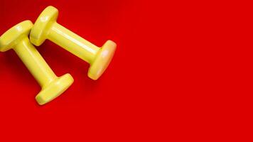 two yellow dumbbells on red background.wide banner photo