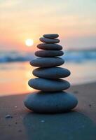 Stack of seven gray stones on the sand, with the sea in the background and the sun setting in the horizon photo