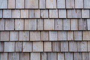 Textured wooden shingles covering a rustic building exterior during daylight hours photo