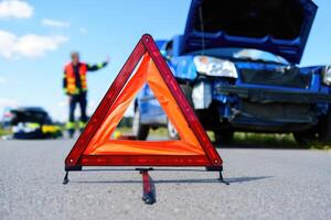 Car accident scene with warning triangle and emergency response in background photo