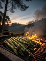 Grilling fresh asparagus over open flame during sunset in a garden setting photo