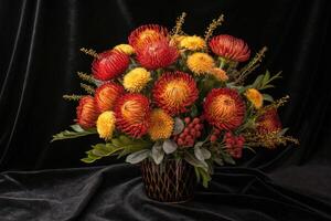 A beautiful floral arrangement of red and yellow protea and chrysanthemums in a vase. photo