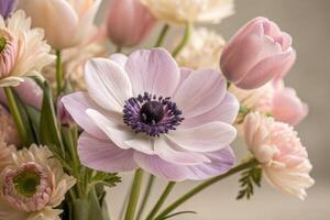 A stunning bouquet of anemones, tulips, and ranunculus, bathed in soft pastel colors. photo