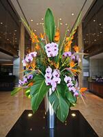 Elegant floral arrangement with orchids and tropical flowers in a stylish modern lobby. photo