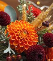 An eye-level, detailed photograph captures an arrangement of colorful dahlias and grains. photo