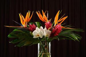 A stunning bouquet of exotic tropical flowers, elegantly arranged in a glass vase, on display. photo