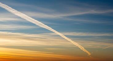 A plane flying over a blue sky with contrails photo