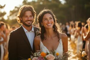 a bride and groom walking down a boho inspired aisle, lined with dried grass and lanterns, family and friends clapping, sunny outdoor atmosphere photo