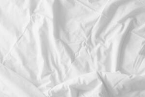 Abstract pattern of white crumpled bed sheet. White wrinkled fabric texture rippled surface. Close up image. photo