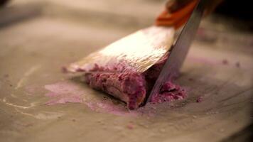 An ice cream vendor uses a spatula to remove ice cream from a cold surface video