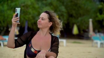 Girl on the beach in windy weather talking and filming on her phone video