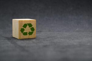 Recycle symbol on wooden cube on dark cover background. Reuse, reduce and recycle concept. photo