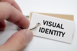Visual identity concept presented on white notepad with hand holding it in clean workspace. photo